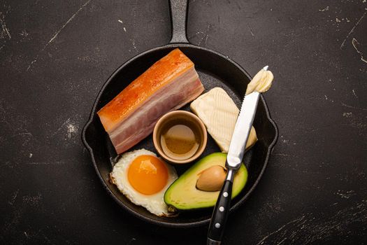 Foods for keto diet in cast iron pan on dark background