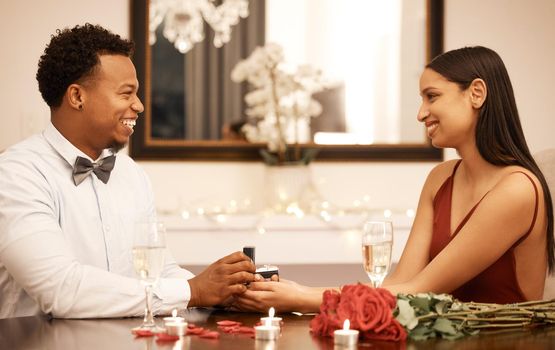 Engagement, proposal ring and couple on date at restaurant with roses, gift and love celebration. Jewellery in young black man hands, woman or people together at luxury table with candles and bouquet