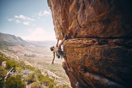 Rock climbing, rope and fearless mountain climber on a cliff, big rocks and risky challenge alone in summer. Mountaineering, bouldering and strong man training his body for balance outdoors in nature