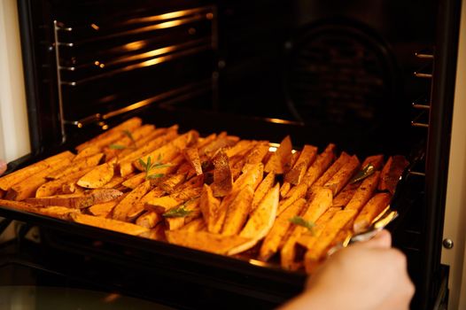 Focus on sliced wedges of batata, sweet potatoes, seasoned with spices and culinary herbs, sprinkled with olive oil