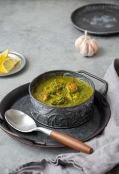 Indian dish Palak Paneer in bowl on grey stone table
