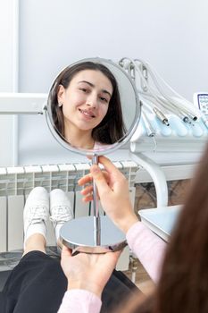 Young woman looking in the mirror after a dental procedure