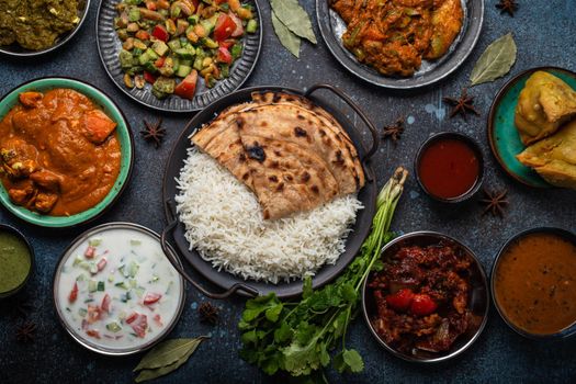 Assorted Indian ethnic food buffet on rustic concrete table from above