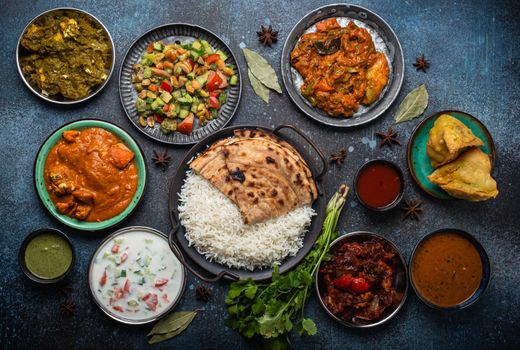 Assorted Indian ethnic food buffet on rustic concrete table from above