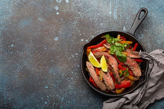 Mexican dish fajitas in cast iron pan from above copy space