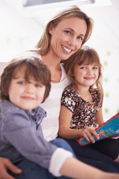 We love story itme. a mother reading with her children at home.