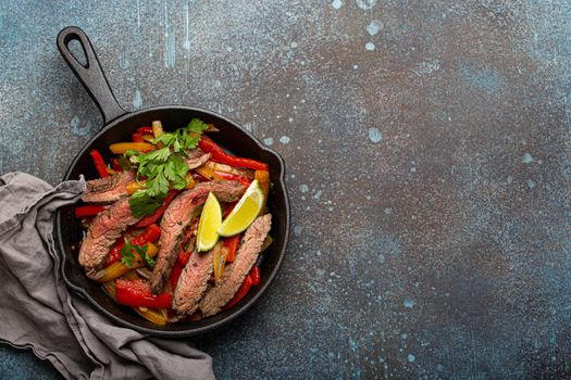 Mexican dish fajitas in cast iron pan from above copy space