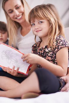 Storytime with mom. Portrait of a young girl reading to her mother and brother