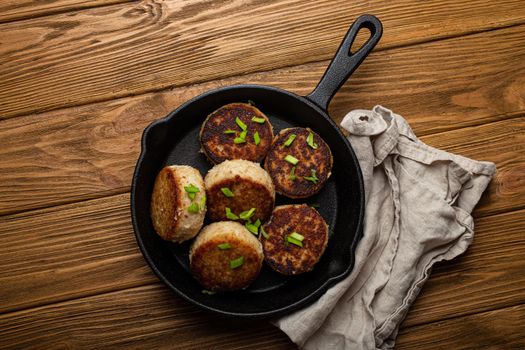 Homemade cutlets from fish, chicken or meat on black cast iron frying pan skillet