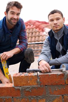 We build solid walls. Portrait of a bricklayer and his apprentice at work.