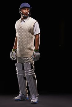 Kitted up. A cropped shot of an ethnic young man in cricket attire isolated on black.