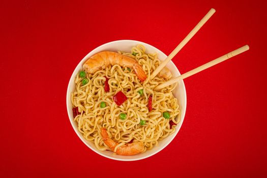 Asian noodles with shrimps in bowl, minimal red background