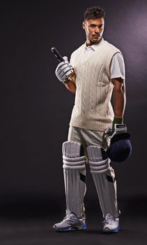 Going out to bat. A cropped shot of an ethnic young man in cricket attire isolated on black.