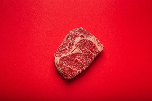 Raw meat beef prime cut steak Ribeye on clean red background from above, beefsteak concept banner minimalism