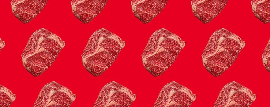 Pattern made of raw meat beef marbled prime cut steak Ribeye on red clean background