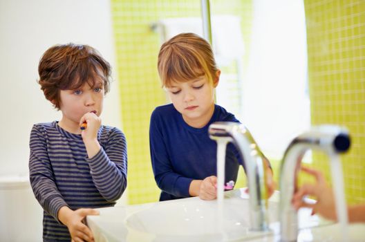 Brushing before bedtime. a brother and sister brushing their teeth at home.