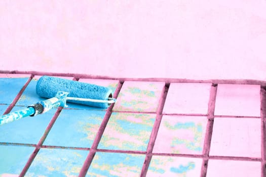 Roller painting pink wall surface with azure blue paint