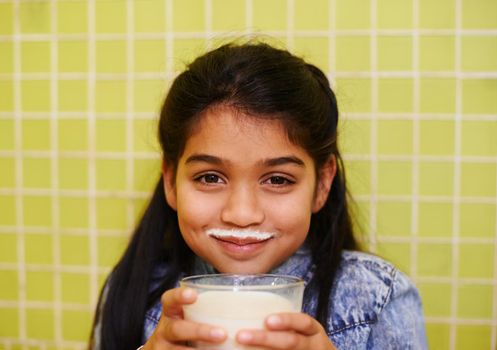 Happy days of childhood. a cute little girl enjoying a milkshake at home.