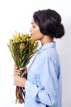 Basking in natures aroma. Studio shot of an attractive young ethnic woman holding a bouquet of flowers.