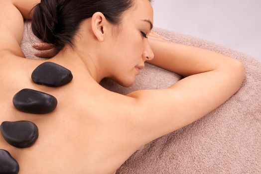 Soothing stones. a young woman enjoying some hot stone therapy.