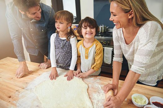 Happiness is a kitchen full of family. a family enjoying pizza at home.
