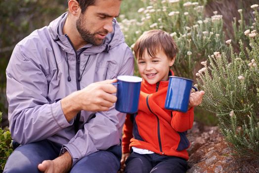 Heres to a great hiker. a happy father and son having something to drink while on a hike together.