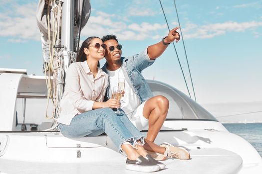 Happy couple, travel and yacht in the ocean for a summer romance on lovely luxury holiday vacation. Smile, sunglasses and young woman enjoying champagne with boyfriend sailing on a cruise date at sea.
