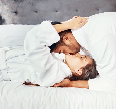Love, spa and couple kiss on honeymoon in a hotel bedroom before luxury, relax and romance on vacation. Travel, robes and young woman on holiday at a wellness lodge resort with a passionate partner