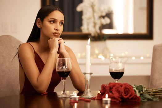 Wine, candle and roses, a woman waiting for date in a romantic restaurant. Engagement or valentines, a beautiful lady, sad and annoyed alone at a table. Rose petals, disappointment and a romance fail.