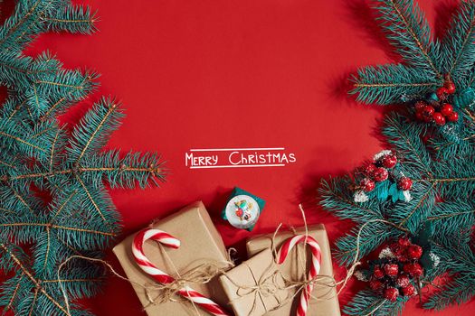 Fir branch and gift box on red background. The inscription - Merry Christmas