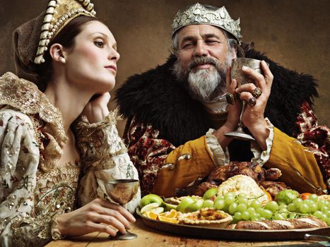 Theres more to rule than feasting, isnt there. A bored queen sitting alongside her husband at a banquet.