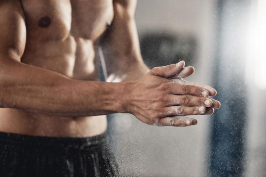 Man with sports chalk powder on his hands in the gym during a fitness training or workout. Closeup of a muscular guy with active, healthy and wellness lifestyle preparing for boxing or weightlifting