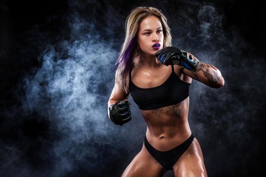 Aggressive sportsman woman boxer fighting on black background with smoke. Copy Space. Boxing sport concept..