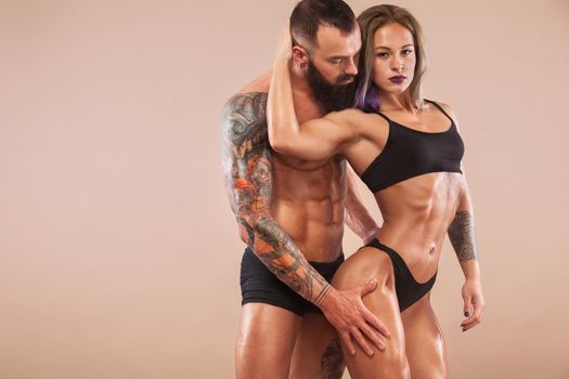 Muscular young fitness sports man and woman with strong fit body on light background.