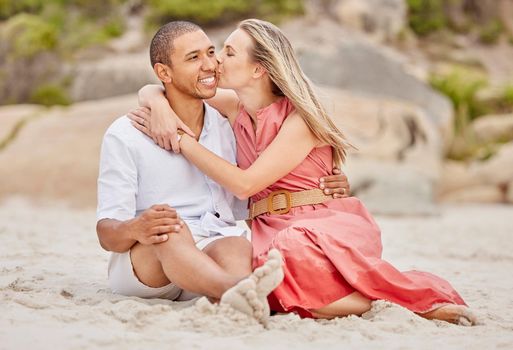 Kiss, love and couple on beach sand with happy smile for holiday or vacation together. Healthy happiness and interracial man and woman or people relax on ground for wellness lifestyle