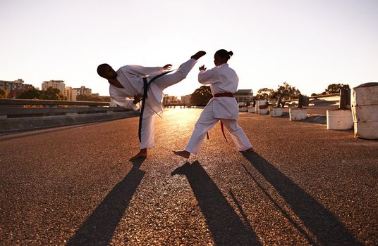 Facing off...Two sportspeople facing off and practicing their karate while wearing gi.