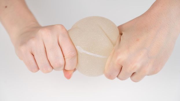 Caucasian woman testing the strength of a breast implant.