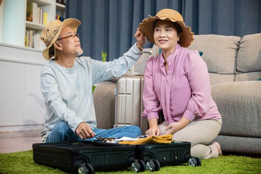 Romantic mature retired packing clothes travel bag suitcase together on floor at home for holiday, Asian couple old senior married retired couple smiling prepare luggage suitcase arranging for travel