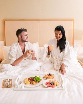 couple having breakfast in bed, men and women in bedroom having breakfast in the morning