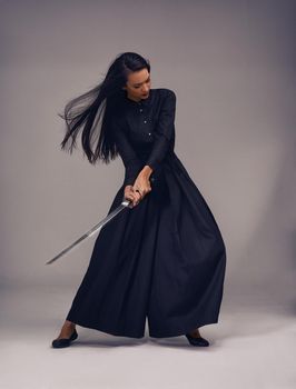 Flawless technique. Studio shot of a beautiful young woman in a martial arts outfit wielding a samurai sword.