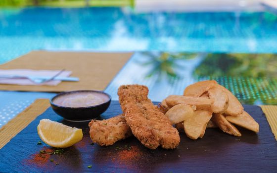 Fish and chips on a plate isolated by the pool