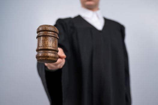 Faceless female judge in a robe holding a court gavel.
