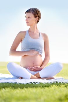Yoga for two. a beautiful pregnant woman doing yoga outdoors