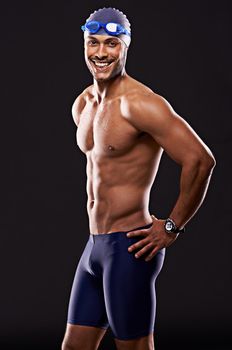 So, wheres a pool I can dive into. Studio shot of a handsome swimmer against a black background.
