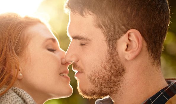 Lets get lost in our lips. a happy young couple sharing a kiss outdoors.