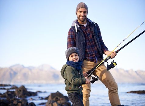 Come join us. Portrait of a father and his little boy fishing by the sea.