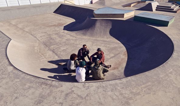 Its a great place to skate. a group of friends hanging out in the sun at a skate park.