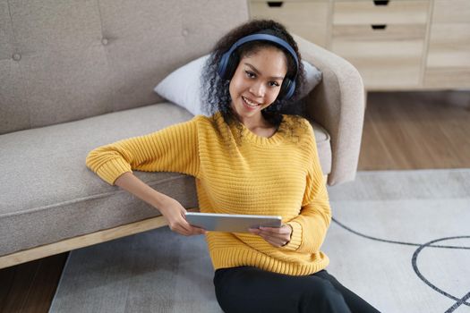 African American wearing headphones and using tablet smiling happily
