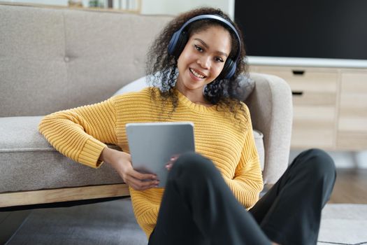 African American wearing headphones and using tablet smiling happily