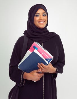 Shes an A student. Portrait of a young muslim woman wearing a burqa holding documents.